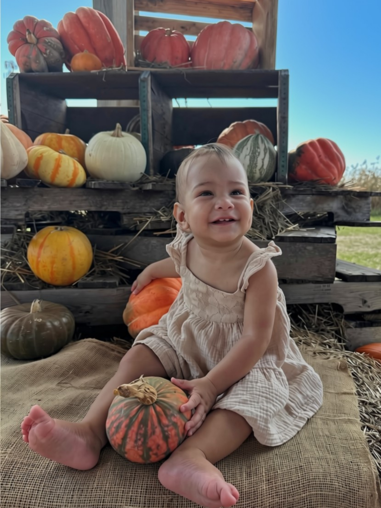 A beautiful baby girl posing for pictures at a pumpkin display at Dade City Farms in Florida